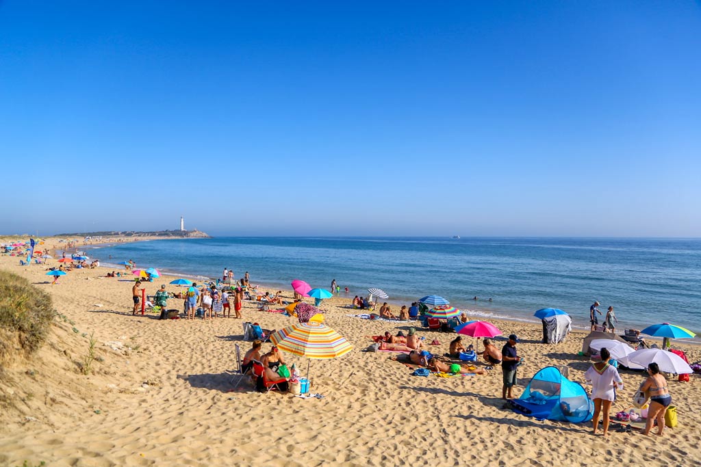 La playa de Zahora en verano con gente y el faro de Trafalgar al fondo